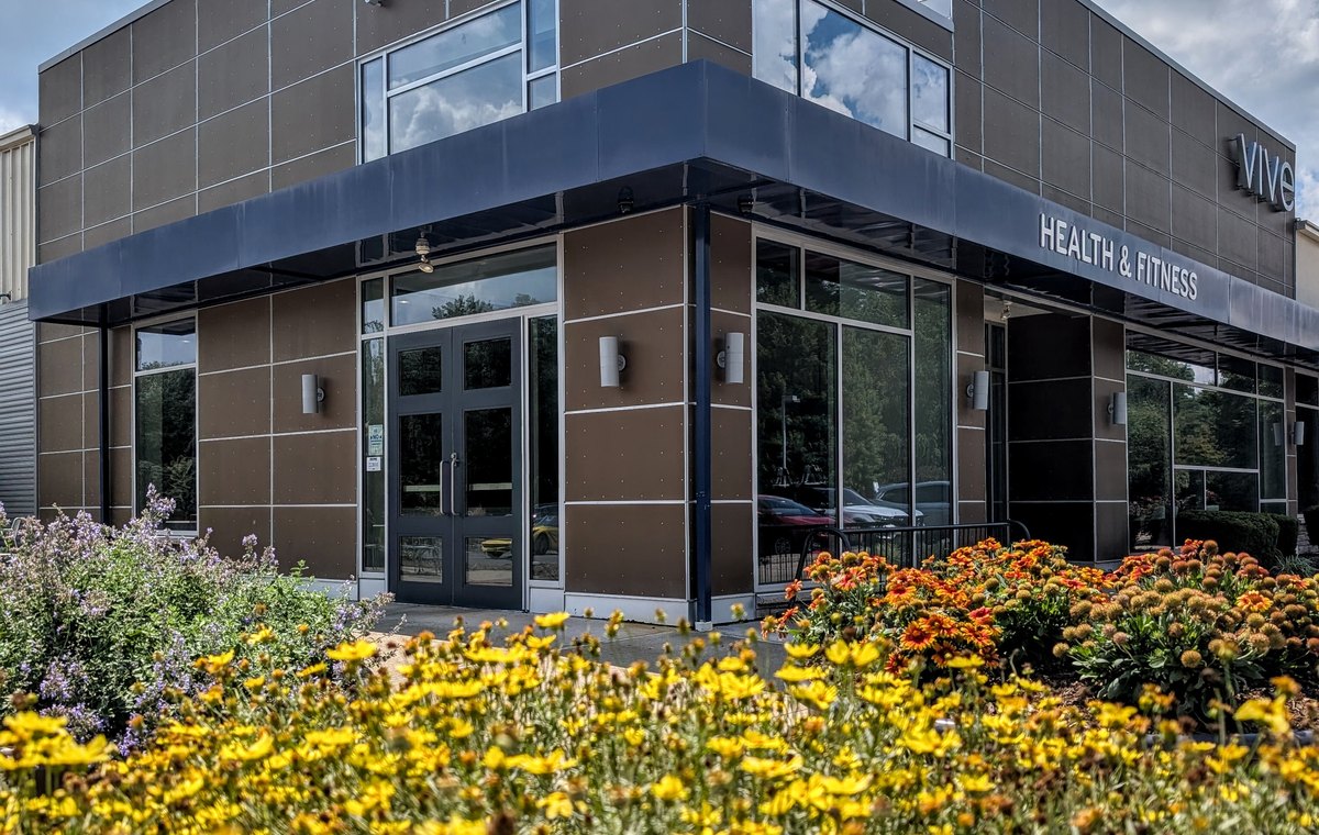 The front entrance of VIVE Health and Fitness with yellow flowers in bloom