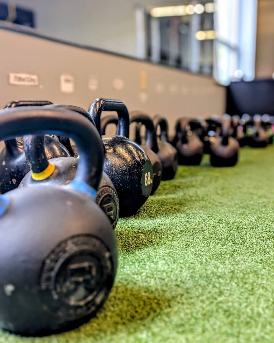 Kettlebells lined up on the performance turf for VIVE Arena LIFT