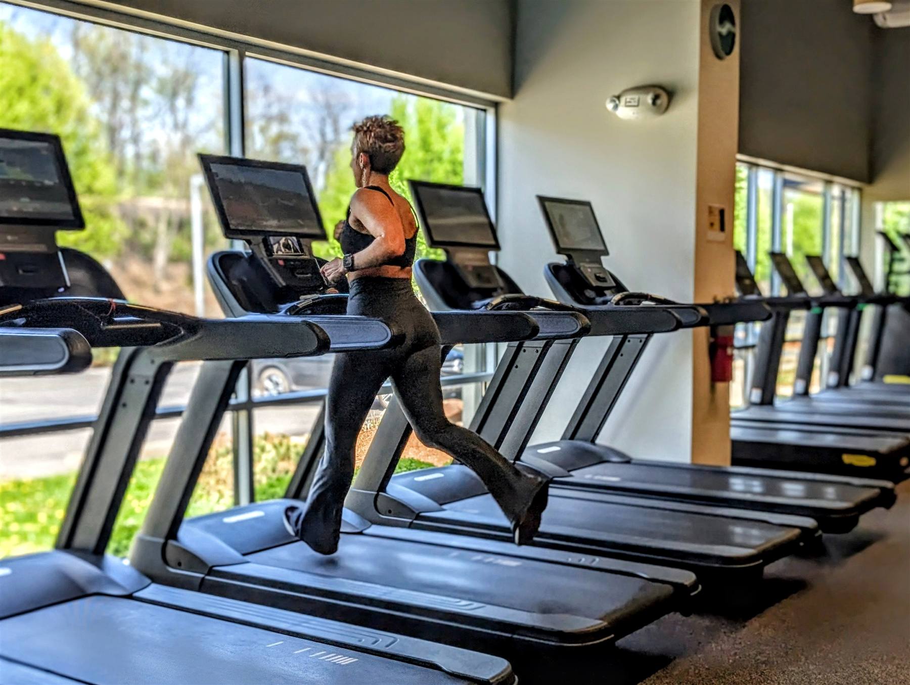 Member running on Technogym treadmills on the sunlit cardio deck at VIVE Health & Fitness
