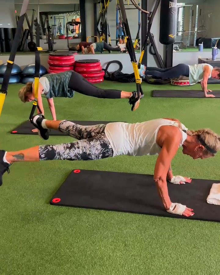 Members holding a plank in a TRX class on the turf
